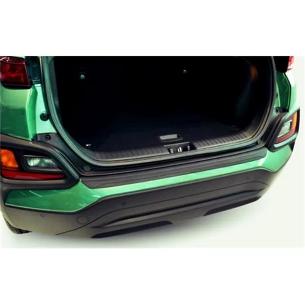 the open trunk of a bright green SUV, likely a Hyundai Kona. The view focuses on the lower edge of the trunk opening and the rear bumper area. A boot sill protector is installed along the threshold where the vehicle’s cargo area meets the bumper. The protector is a narrow, dark-colored strip—likely made of durable plastic or metal—that spans the width of the loading edge. Its purpose is to prevent scratches, dents, and paint damage when loading or unloading heavy or abrasive items. The protector has a slightly textured surface, which improves grip and adds subtle detail without affecting the vehicle’s overall aesthetics. This accessory is especially helpful for individuals who frequently use the trunk space, such as pet owners, cyclists, or those with limited lifting ability, as it makes it safer and easier to slide items in and out without damaging the car.