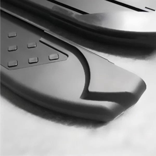 This image displays the end portion of two matching black side steps resting on a soft white surface. Each step has a gently curved cap at the end and a textured section with several square rubber grips. The caps provide a smooth finish and enhance safety by covering any sharp edges. The design is minimal and rugged, emphasizing function over decoration.