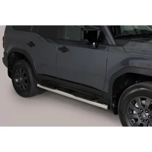 Passenger-side view of a 2025 Toyota Land Cruiser 250 in dark grey, showing compact stainless steel side steps mounted below the doors to assist entry and exit.