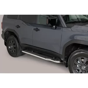 Passenger-side view of a 2025 Toyota Land Cruiser 250 in grey, equipped with long stainless steel side steps installed below the doors to assist with cabin access.